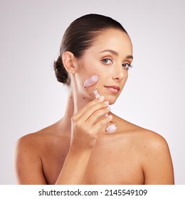 This Is How My Skin Care Rolls. Shot Of An Attractive Young Woman Using A Jade Roller On Her Face Against A Studio Background.