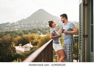 This is how we spend our weekends. Shot of an affectionate young couple drinking coffee while standing on their balcony at home in the morning. - Powered by Shutterstock