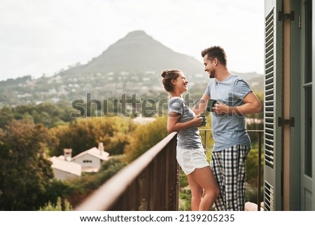 This is how we spend our weekends. Shot of an affectionate young couple drinking coffee while standing on their balcony at home in the morning.