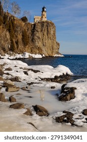 This is the iconic 1910 Split Rock Lighthouse on Lake Superior near Two Harbors, Minnesota in the middle of winter. A magnificent lighthouse completed in 1910 in a spectacular setting enhanced by lots of ice and white snow.  It was built to protect ships from the treacherous rocky coast after the devastating Mataafa Storm of 1905 that wreaked havoc and wrecked nearly 30 ships along Lake Superior's rocky coastline. There were no roads there at the time and 310 tons of materials were hoisted up the 133 foot sheer cliff from supply boats. The 133 foot shear cliff  the lighthouse sits on is most dramatic viewed from the lower lake shore area. Hiking here in winter can be a little treacherous with very large, rough rocks covered in thick ice and snow with the open lake waters right at the edge of the treacherous shore..