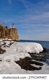 This is the iconic 1910 Split Rock Lighthouse on Lake Superior near Two Harbors, Minnesota in the middle of winter. A magnificent lighthouse completed in 1910 in a spectacular setting enhanced by lots of ice and white snow.  It was built to protect ships from the treacherous rocky coast after the devastating Mataafa Storm of 1905 that wrecked nearly 30 ships along Lake Superior's rocky coastline. There were no roads there at the time and 310 tons of materials were hoisted up the 133 foot sheer cliff from supply boats. The 133 foot shear cliff  the lighthouse sits on is most dramatic viewed from the lower lake shore area. Hiking here in winter can be a little treacherous with very large, rough rocks covered in thick ice and snow with the open lake waters right at the edge of the treacherous shore..