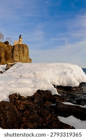 This is the iconic 1910 Split Rock Lighthouse on Lake Superior near Two Harbors, Minnesota in the middle of winter. A magnificent lighthouse completed in 1910 in a spectacular setting enhanced by lots of ice and white snow.  It was built to protect ships from the treacherous rocky coast after the devastating Mataafa Storm of 1905 that wrecked nearly 30 ships along Lake Superior's rocky coastline. There were no roads there at the time and 310 tons of materials were hoisted up the 133 foot sheer cliff from supply boats. The 133 foot shear cliff  the lighthouse sits on is most dramatic viewed from the lower lake shore area. Hiking here in winter can be a little treacherous with very large, rough rocks covered in thick ice and snow with the open lake waters right at the edge of the treacherous shore.