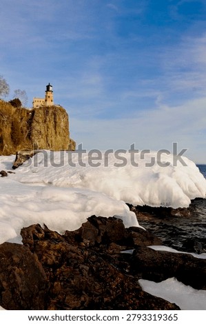 This is the iconic 1910 Split Rock Lighthouse on Lake Superior near Two Harbors, Minnesota in the middle of winter. A magnificent lighthouse completed in 1910 in a spectacular setting enhanced by lots of ice and white snow.  It was built to protect ships from the treacherous rocky coast after the devastating Mataafa Storm of 1905 that wrecked nearly 30 ships along Lake Superior's rocky coastline. There were no roads there at the time and 310 tons of materials were hoisted up the 133 foot sheer cliff from supply boats. The 133 foot shear cliff  the lighthouse sits on is most dramatic viewed from the lower lake shore area. Hiking here in winter can be a little treacherous with very large, rough rocks covered in thick ice and snow with the open lake waters right at the edge of the treacherous shore.