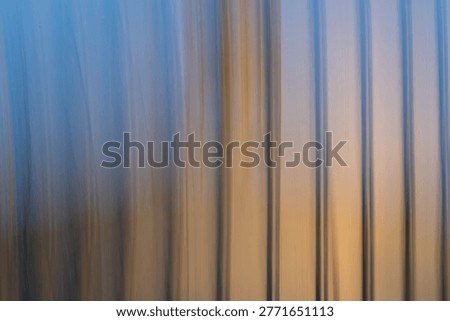 This image is a captivating example of Intentional Camera Movement (ICM) photography, featuring a series of vertical, blurred lines that create a rhythmic, painterly effect. The color palette transitions beautifully from a cool, ethereal twilight blue at the top to a warm, glowing amber and gold at the base. The soft, streaked textures evoke a sense of fluid motion and abstract tranquility, blurring the line between photography and contemporary digital art. The vertical flow and soft focus create a calming, Zen-like quality. The minimalist composition and elegant color gradient feel modern and high-end. The abstraction hides the original subject, inviting the viewer to interpret the forms as anything from a forest at dusk to light reflecting off water. Perfect as large-scale wall art for modern offices, spas, or minimalist living spaces to promote a calm environment. An ideal hero background for websites focusing on wellness, technology, or creative portfolios where text needs to be overlaid. A striking cover or background for magazines discussing mental health, philosophy, or abstract art. A sophisticated background for high-end skincare or organic product labels.