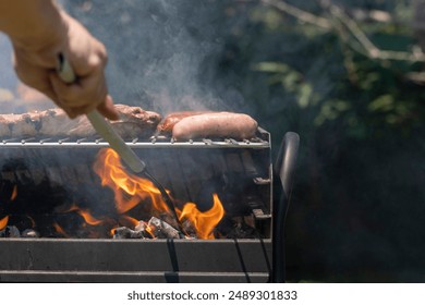 This image captures a barbecue scene with raw ribs and sausages being grilled over a charcoal fire, representing a typical outdoor cooking experience and social gathering activity. - Powered by Shutterstock