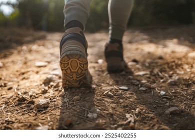 This image captures the close up view of a unknown man wearing hiking boots walking on a rocky and dirt path, emphasizing the rugged terrain and outdoor adventure - Powered by Shutterstock