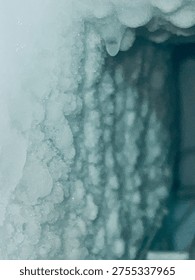 This image captures a close-up view of icicles hanging from a frozen surface, showcasing the intricate details of ice formations in a winter wonderland. The delicate, crystalline structures glisten in the light, evoking a sense of serenity and tranquility. The frozen landscape is a testament to the beauty of nature in the cold winter months.