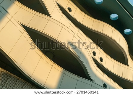 This image captures the elegant lines and curves of a modern building facade, showcasing unique architectural design under soft sunlight and shadow play.