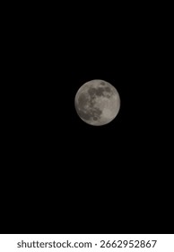 This image captures a full moon glowing brightly against a pitch-black night sky. The moon is centered, showing its surface in beautiful detail — you can see the dark patches (lunar maria) and lighter