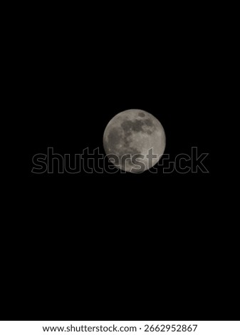 This image captures a full moon glowing brightly against a pitch-black night sky. The moon is centered, showing its surface in beautiful detail — you can see the dark patches (lunar maria) and lighter