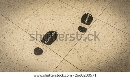this image captures an innovative wayfinding system, featuring bold footsteps on a clean floor, leading guests towards an event or display area.