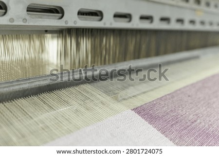 This image captures the intricate process of weaving at a wool production factory, showcasing the spinning machine in action for textile manufacturing.