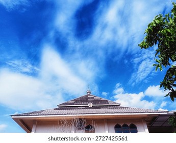 This image captures a low-angle view looking up at the roof of a building—likely a mosque, indicated by the small decorative dome and crescent finial atop the main roof structure