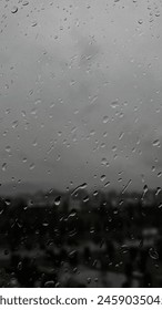 This image captures raindrops clinging to a window against a backdrop of a gloomy, overcast sky, portraying a melancholic and tranquil scene.