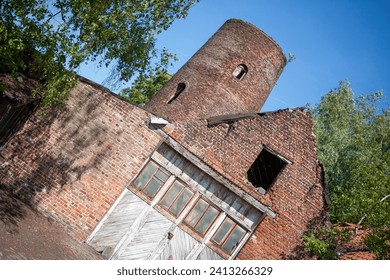 This image captures the remains of what was once a brick windmill, standing against a backdrop of clear blue skies. The structure, although in ruins, conveys a strong sense of history and nostalgia