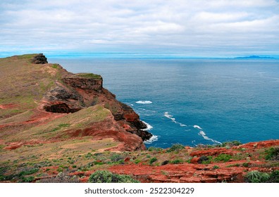 This image captures rugged coastal cliffs that jut out into a serene blue ocean, with the clear sky above, reflecting nature’s raw beauty and serene majesty, creating a peaceful scene. - Powered by Shutterstock