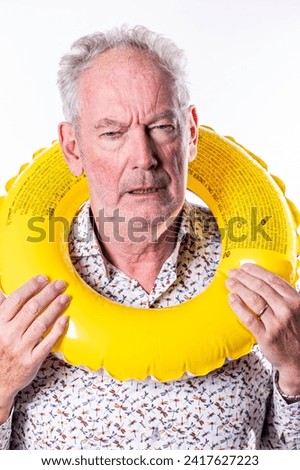 This image captures a senior man with a skeptical or uncertain expression while holding a yellow swim ring around his neck. The contrast between the bright, playful object and his dubious expression