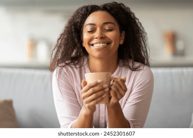 This image captures a serene african american lady enjoying a warm beverage at home, embodying relaxation and comfort - Powered by Shutterstock