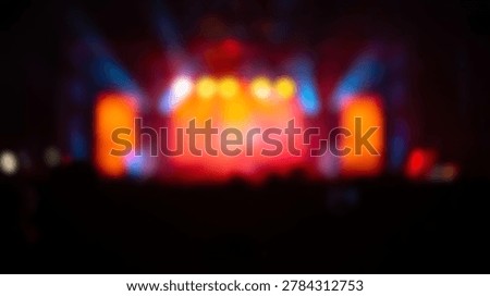 This image captures the vibrant and dynamic atmosphere of a concert, with blurred stage lights creating a colorful and energetic visual experience. The lights illuminate the stage.