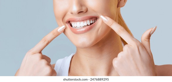 This image is a close up of a woman face. Her fingers are resting on her cheeks, and she is smiling widely, showing off her bright white teeth, cropped - Powered by Shutterstock