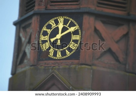 This image is a close-up of an antique clock face with Roman numerals and golden hands mounted on an old cathedral building. it has an antique appearance.