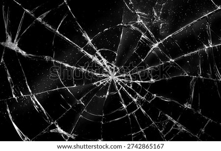 This image depicts a completely shattered glass surface, showcasing a burst of cracks originating from a central point of impact.