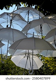 This image depicts objects that look like lanterns or ornaments hanging on the ceiling. These items are shaped like white umbrellas and have patterns that look like letters or symbols.