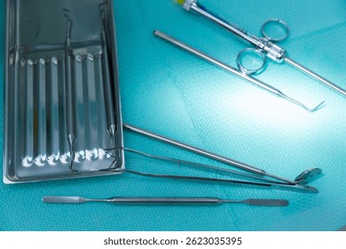 This image displays an array of dental instruments, including mirrors and probes, arranged systematically on a turquoise surgical surface, highlighting their importance in oral health.