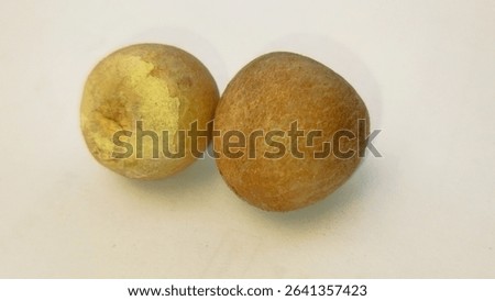 This image displays two roundish, light brown or yellowish-brown fruits against a clean white background. The fruit on the left has a lighter, somewhat yellowish tone, with a visible, slightly irregul