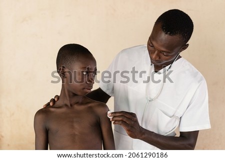 In this image, a doctor is disinfecting the injection site on a black boy's arm after malaria vaccination in West Africa