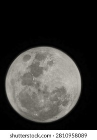 This image features a closely cropped, full view of the Moon isolated against a pitch-black background, showing an even illumination typical of a full moon phase. The view appears to be optically inverted or flipped—common when captured through a telescope—which positions the prominent, dark gray lunar maria on the left and lower portions of the disc. While the focus is slightly soft, the image clearly highlights the contrast between these smooth, dark plains and the brighter, heavily cratered lunar highlands.