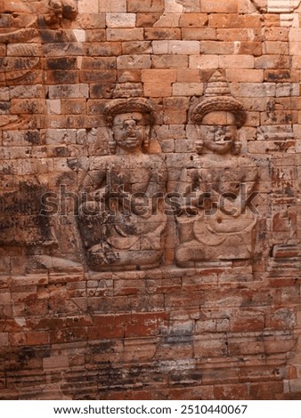 This image features a close-up of a bas-relief sculpture carved into a stone wall. The sculpture depicts a female figure with intricate details, including her headdress, jewelry, and clothing. The fig