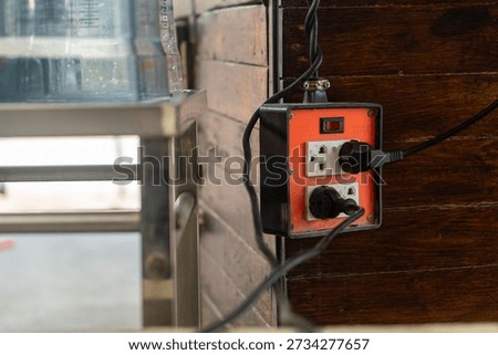 This image features a close-up of an electrical outlet on a wooden wall, showcasing the plug and power cord in a functional and industrial setting.