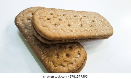 This image features a close-up, high-angle shot of two rectangular biscuits (cookies) stacked slightly askew on a plain white surface