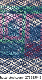 This image features a close-up view of a vibrant blue chain-link fence or metal mesh structure. The interwoven metal wires form a repeating diamond-shaped pattern, creating a strong geometric texture. The bright blue coating enhances its visual appeal while providing protection against weather and corrosion. The detailed perspective highlights the fence's sturdy construction, making it suitable for security, boundary marking, gardening, or decorative applications. The uniform mesh design creates an eye-catching abstract pattern with depth and symmetry.