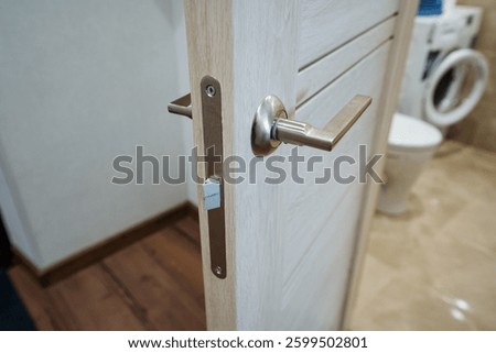 This image features a closeup view of a bathroom door, showcasing its intricate handle and details. The context suggests the presence of wood elements, adding to the overall ambiance of the room