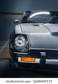 This image features the front of a classic car, with a prominent circular headlight, parked indoors.