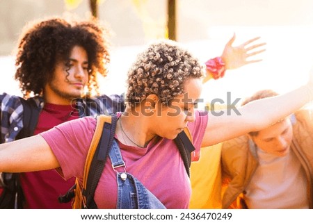 This image features a group of young friends in a moment of relaxation and interaction during an outdoor adventure. Backlit by the sun, the photograph captures the intimate dynamics of the group. A