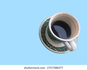 This image features a high-angle, top-down view of a demitasse cup and matching saucer set against a solid light blue background.
