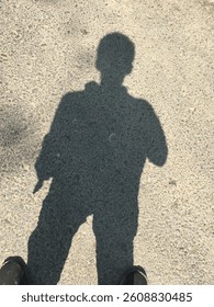 This image features a man's shadow cast on the ground under bright sunlight. the dramatic silhouette of the person creates a striking visual effect, perfect for projects focused on light, shadow, and 