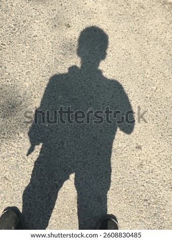 This image features a man's shadow cast on the ground under bright sunlight. the dramatic silhouette of the person creates a striking visual effect, perfect for projects focused on light, shadow, and 