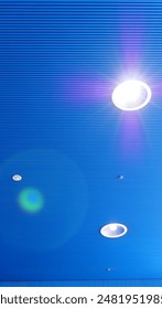 This image features a modern ceiling with bright lights, showcasing a striking blue color and geometric patterns. The minimalist design and clean lines emphasize contemporary architectural aesthetics.