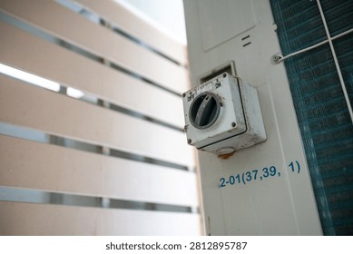 This image features an outdoor electrical utility box mounted on a building exterior wall, showcasing a control device used for power distribution and electrical connections.
