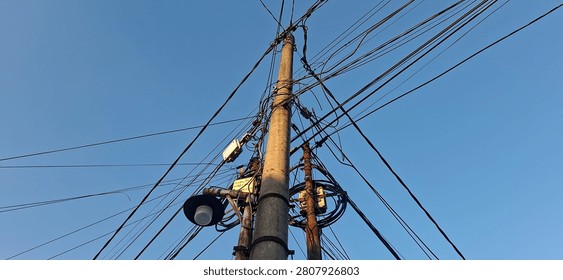 This image features a power pole with complex, jumbled overhead wiring against a clear sky.