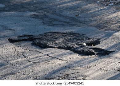 This image features a section of a road displaying an asphalt patch that is marked by visible cracks on the surface, which highlights the ongoing challenges faced in road maintenance efforts