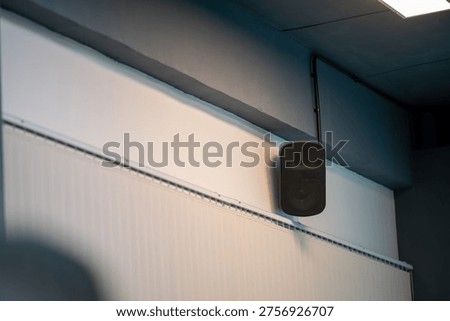 This image features a sleek speaker mounted on a wall in a modern room, showcasing contemporary design and sound technology ideal for creating ambiance.