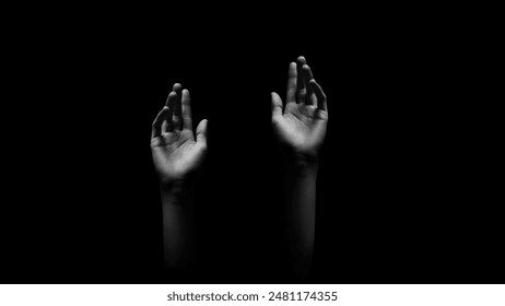 This image features two hands reaching upward, with fingers extended, against a dark, black background. The hands are the main focus of the image, and the darkness adds a sense of mystery