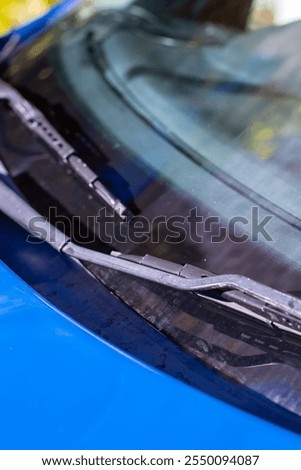 This image features an upclose view of a windshield wiper carefully positioned on a stylish blue car, emphasizing its sleek design