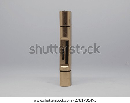 This image features a vertical, metallic object with a brass finish, showcasing intricate details and a minimalist design.