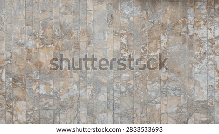 This image features a vertical stone wall cladding with a multi-toned, earthy marble and slate-like pattern in shades of grey, beige, and warm ochre